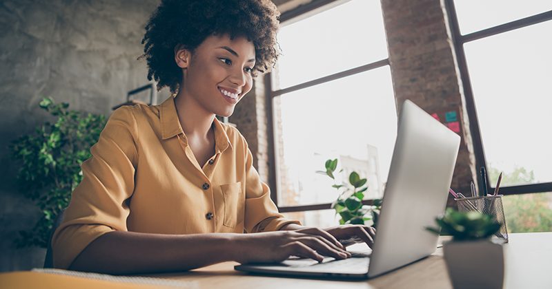 Photo of cheerful positive business lady smiling toothily looking into screen of notebook computer comparing corporate income for previous year with current one