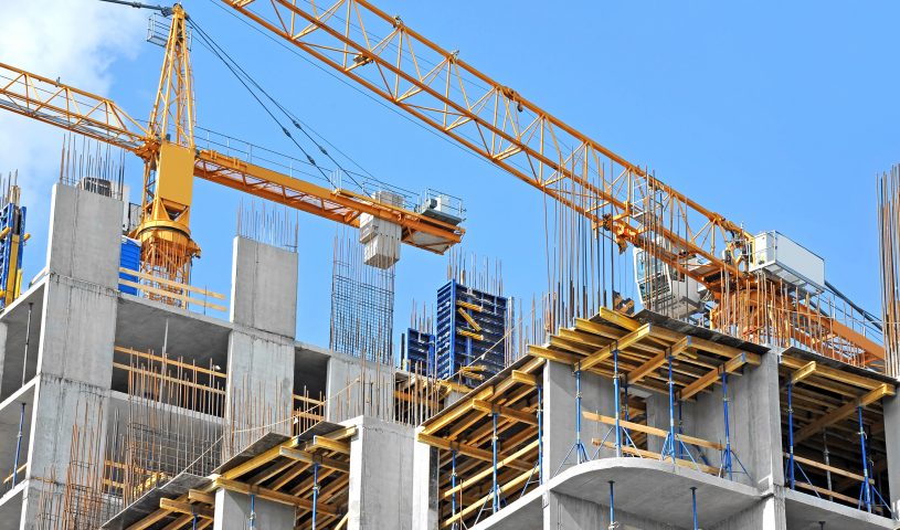 Crane and building construction site against blue sky