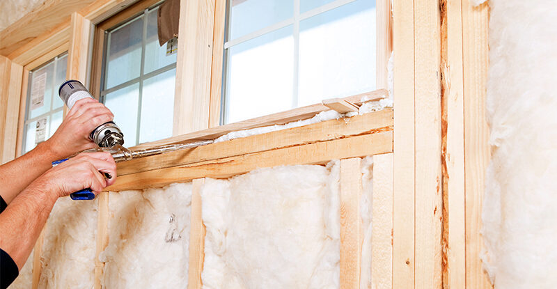 Construction Worker Applying Expandable Foam Insulation to Window
