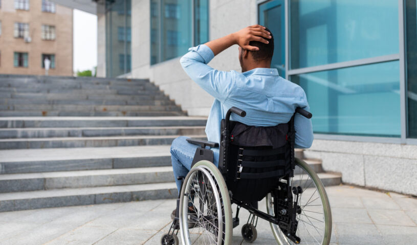 Irritated impaired black man in wheelchair having no possibility to enter building without ramp, outdoors